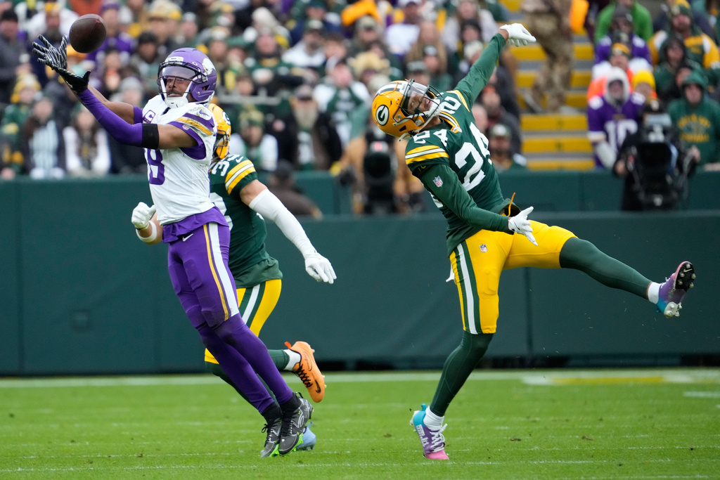 Minnesota Vikings wide receiver Justin Jefferson (18) catches a pass against Green Bay Packers safety Evan Williams (33), back, and cornerback Carrington Valentine (24) during the first half of an NFL football game Sunday, Nov. 23, 2025, in Green Bay, Wis. (AP Photo/Morry Gash)