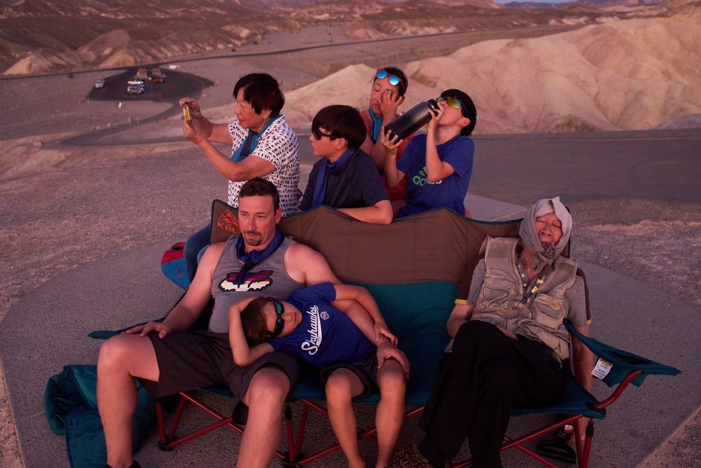 FILE Joe Chyuwei, right, Addison Black, front center, James Black, front left, and back row from left, Helen Chyuwei, Jameson Black, Grace Chyuwei and Grayson Black watch the sunset in the heat at Zabriskie Point, Aug. 3, 2025, in Death Valley National Park, Calif. (AP Photo/John Locher, File)