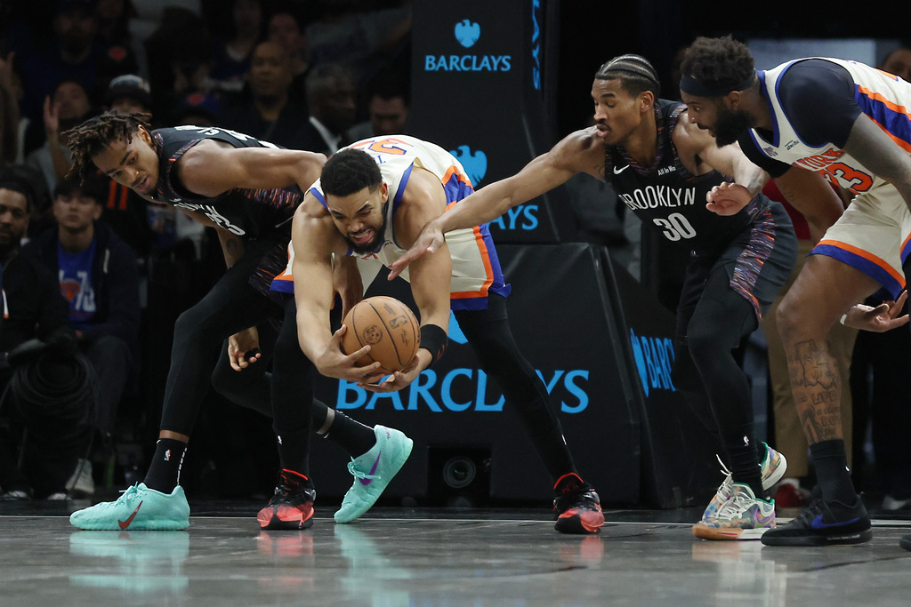 Brooklyn Nets center Nic Claxton, left, and Brooklyn Nets guard Ochai Agbaji (30) reach for the ball against New York Knicks center Karl-Anthony Towns, second from left, during the first half of an NBA basketball game, Friday, March 20, 2026, in New York. (AP Photo/Heather Khalifa)