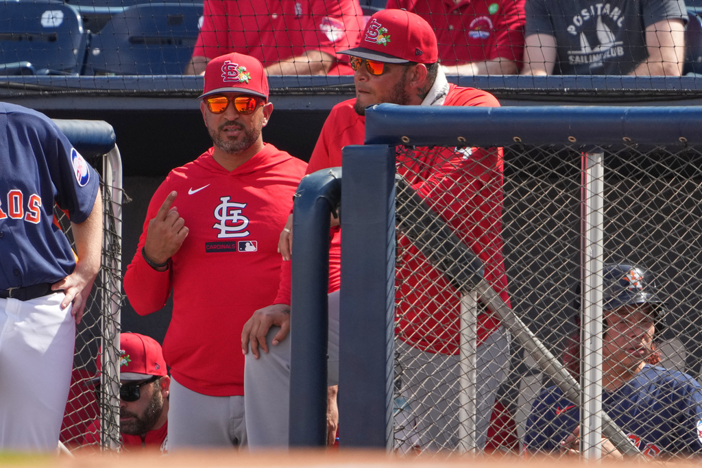 St. Louis Cardinals manager Oliver Marmol, left, and special assistant Yadier Molina watch from the dugout during a spring training baseball game against the Houston Astros Sunday, Feb. 22, 2026, in West Palm Beach, Fla. (AP Photo/Jeff Roberson)