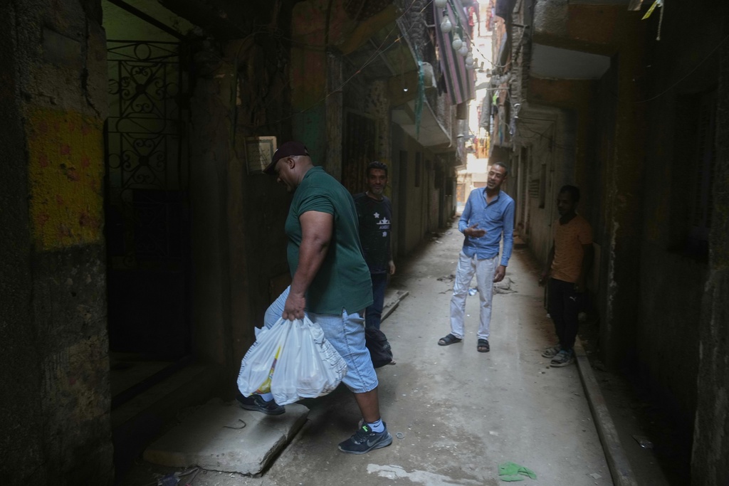 Egyptian wrestler Ashraf Mahrous, also known as Kabonga, is greeted by neighbors as he carries his lunch near his home in Cairo, Egypt, July 24, 2025. (AP Photo/Amr Nabil)