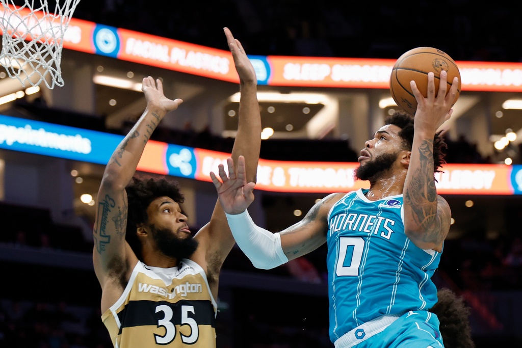 Charlotte Hornets forward Miles Bridges (0) drives to the basket against Washington Wizards forward Marvin Bagley III during the first half of an NBA basketball game in Charlotte, N.C., Tuesday, Dec. 23, 2025. (AP Photo/Nell Redmond)
