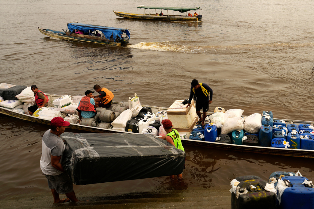 Boatmen operating Catraia, a traditional boat used on the Oiapoque River, prepare for a crossing carrying goods, gasoline canisters and supplies, at a port in the city of Oiapoque, Amapa state, Brazil, Tuesday, March 10, 2026. (AP Photo/Eraldo Peres)