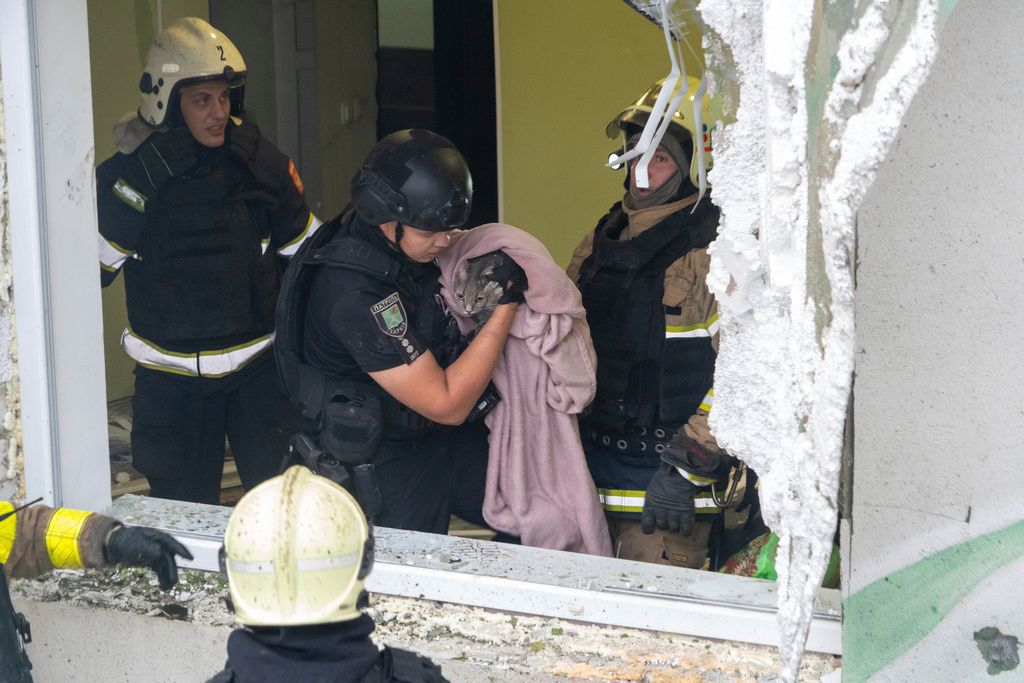 Firefighters evacuate a cat during search and rescue works in the damaged residential building following Russia's missile attack in Kharkiv, Ukraine, Monday, Aug. 18, 2025. (AP Photo/Andrii Marienko)