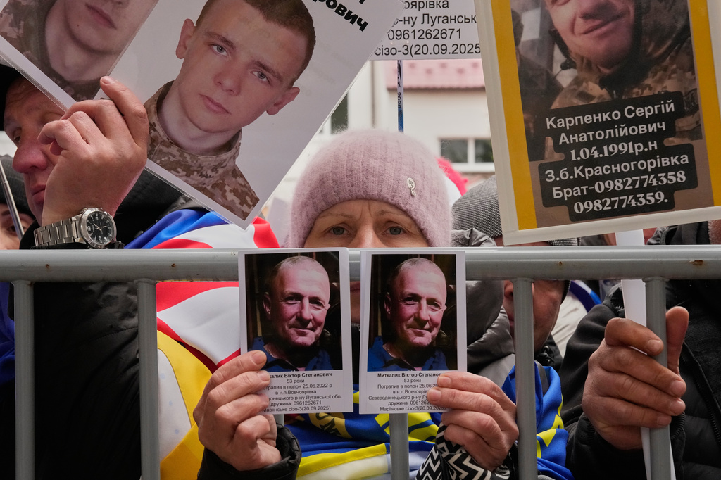 People hold photos of their missed relatives as Ukrainian soldiers return from captivity during a POW exchange between Russia and Ukraine in Chernyhiv region, Ukraine, Saturday, April 11, 2026. (AP Photo/Efrem Lukatsky)