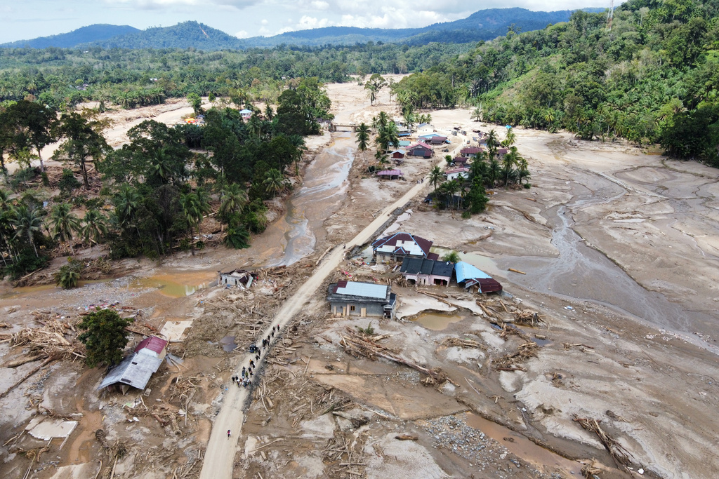 FILE - People walk along a road in a village affected by a flash flood in Batang Toru, North Sumatra, Indonesia, Dec. 1, 2025. (AP Photo/Binsar Bakkara, File)