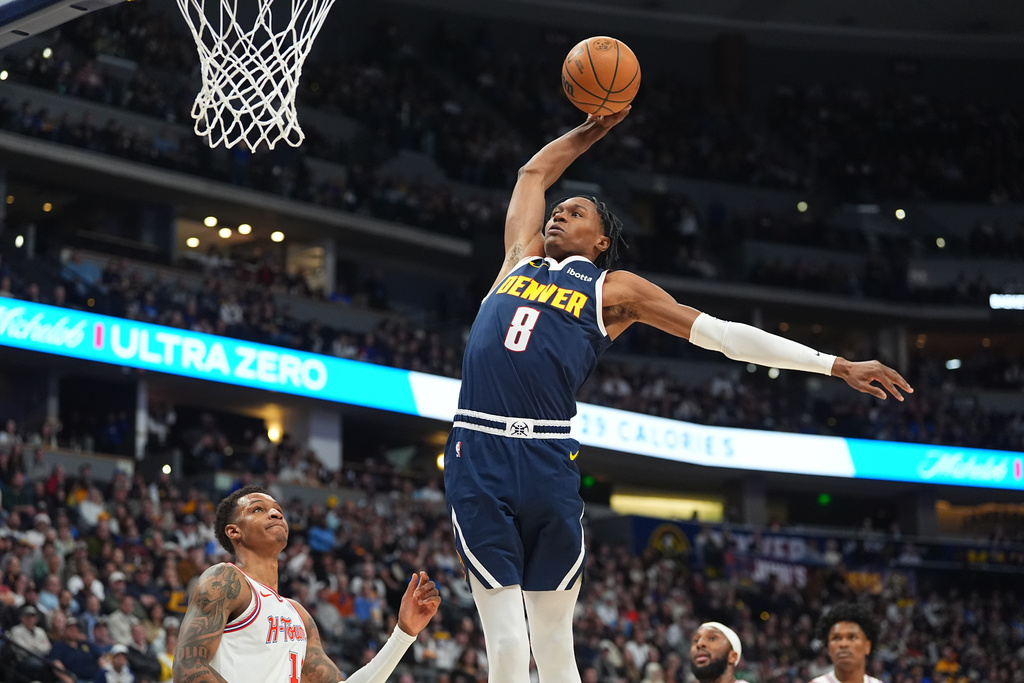 Denver Nuggets guard Peyton Watson (8) goes up to dunk over Houston Rockets forward Jabari Smith Jr., left, in the first half of an NBA basketball game Monday, Dec. 15, 2025, in Denver. (AP Photo/David Zalubowski)