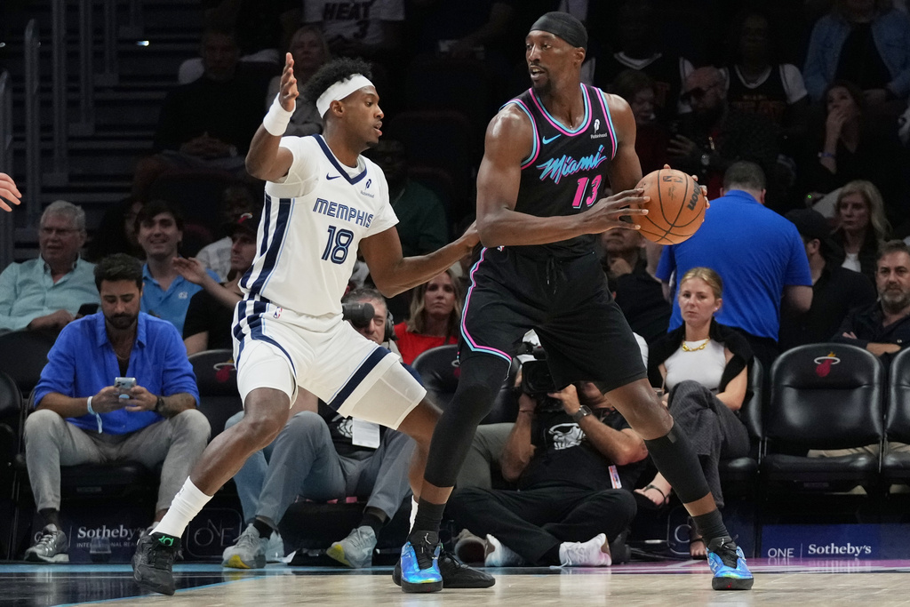 Memphis Grizzlies forward Olivier-Maxence Prosper (18) defends Miami Heat center Bam Adebayo (13) during the first half of an NBA basketball game, Saturday, Feb. 21, 2026, in Miami. (AP Photo/Lynne Sladky)