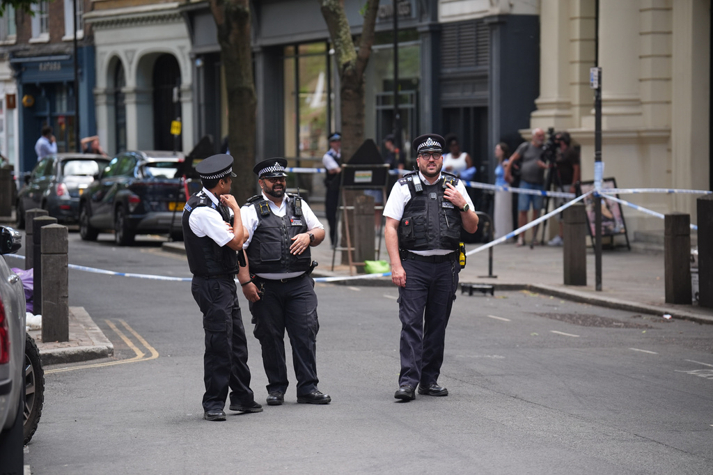 Police officers stand at the scene on Endell Street in Covent Garden, after four men were stabbed, in central London, Wednesday Aug. 5, 2026. PA Photo. (James Manning/PA via AP)
