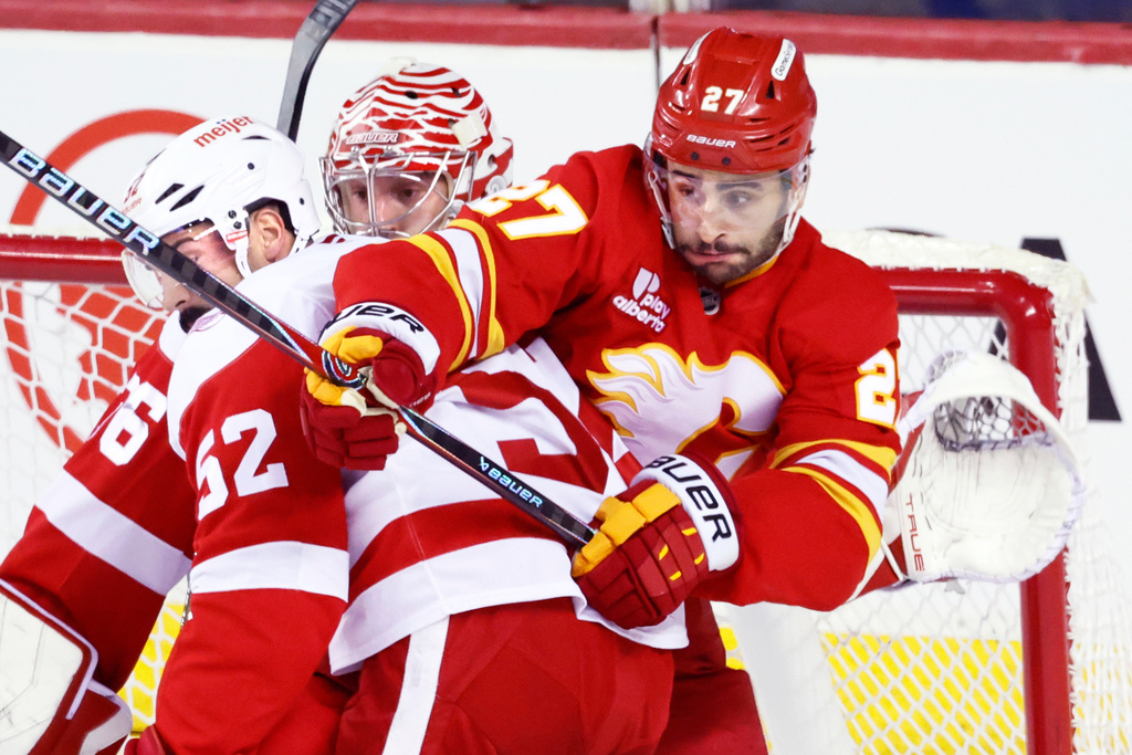 Detroit Red Wings' Travis Hamonic (52) battles with Calgary Flames' Matt Coronato (27) in front of Red Wings goalie John Gibson during the second period of an NHL hockey game in Calgary, Alberta, on Wednesday, Dec. 10, 2025. (Larry MacDougal/The Canadian Press via AP)