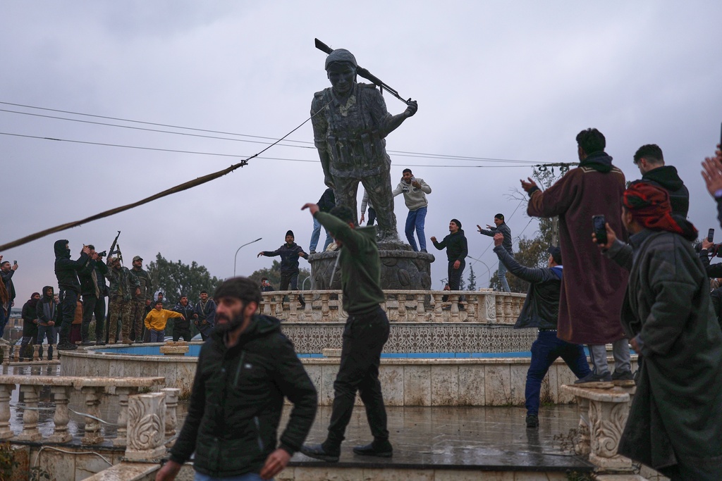 Residents topple a statue of a female Kurdish fighter after the takeover of the town by Syrian government forces from U.S.-backed Syrian Democratic Forces (SDF), in Tabqa, eastern Syria, Sunday, Jan. 18, 2026. (AP Photo/Ghaith Alsayed)