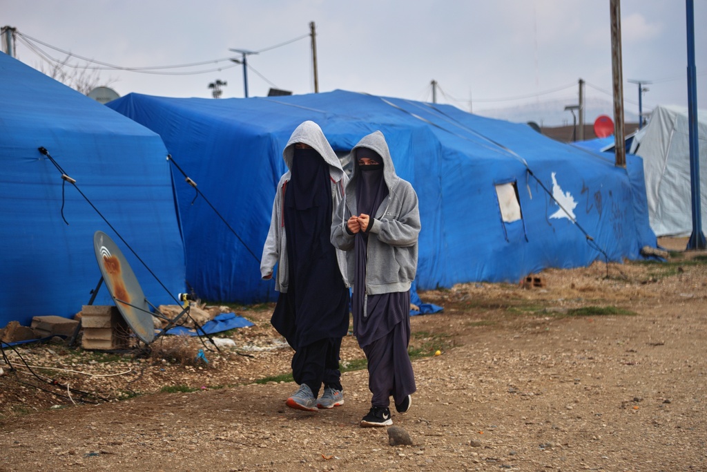 Two women walk among tents at Roj camp, one of the detention facilities holding thousands of Islamic State group members and their families, in the al-Malikiyah area of northeastern Syria, Thursday, Jan. 29, 2026. (AP Photo/Baderkhan Ahmad)