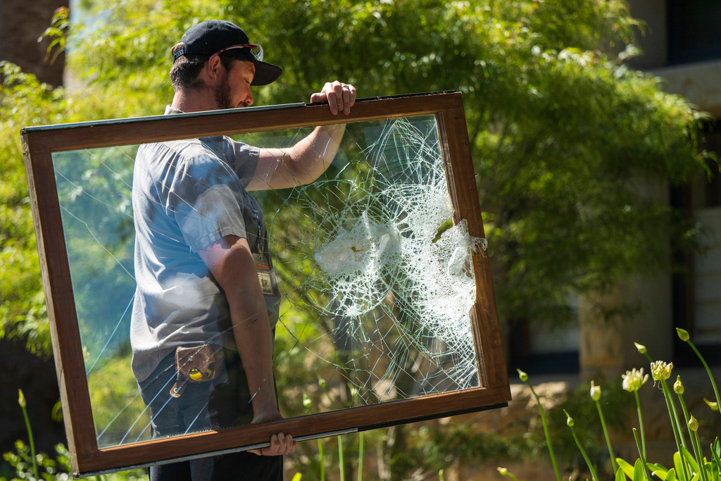 FILE - A campus maintenance worker carries a broken window from the office of the president at Stanford University in Palo Alto, Calif., June 5, 2024. (AP Photo/Nic Coury, File)