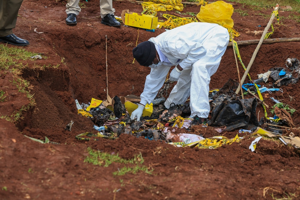 Directorate of Criminal Investigations (DCI) forensic staff inspect the scene of a mass grave where 33 bodies were exhumed at a cemetery in Kericho, Western Kenya Thursday, March 26, 2026. (AP Photo/Andrew Kasuku)