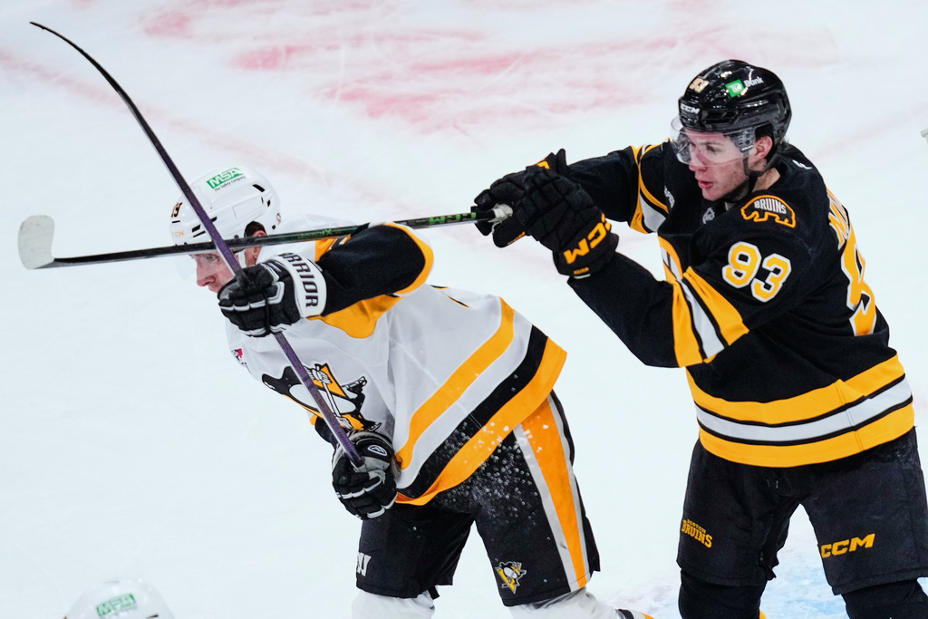 Boston Bruins center Fraser Minten (93) hits Pittsburgh Penguins center Connor Dewar with his stick during the first period of an NHL hockey game, Tuesday, March 3, 2026, in Boston. (AP Photo/Charles Krupa)