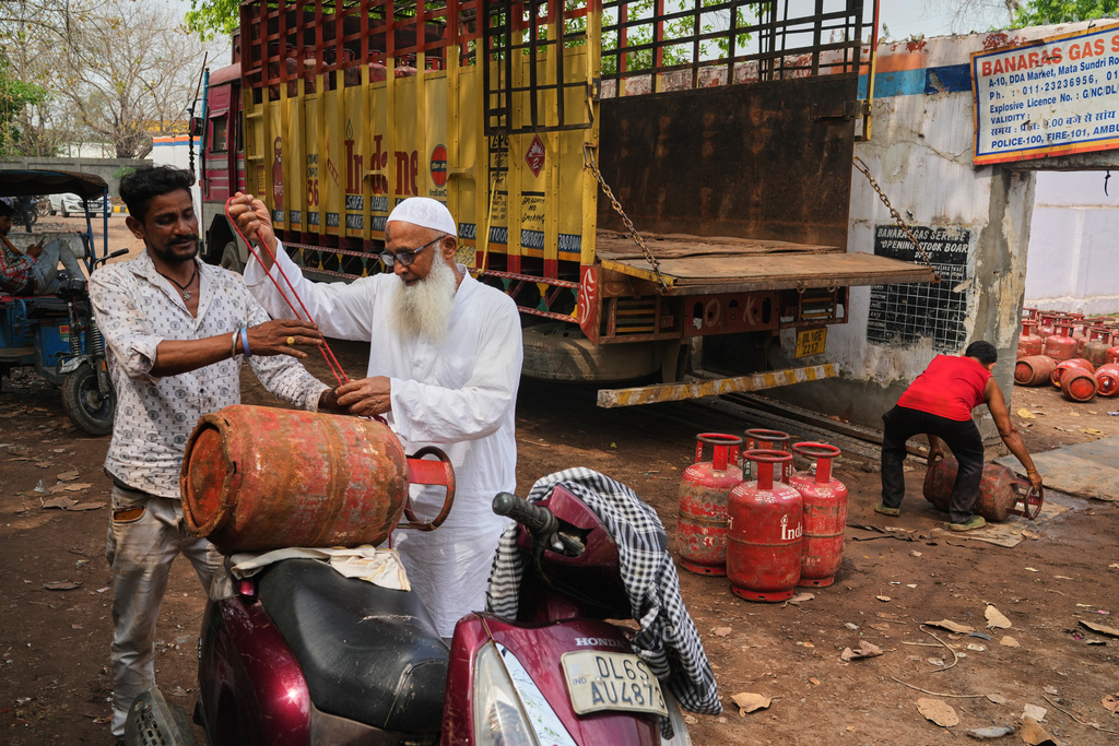 An elderly man ties a gas cylinder to his scooter after collecting it from a depot in New Delhi, Thursday, March 19, 2026. (AP Photo/Manish Swarup)