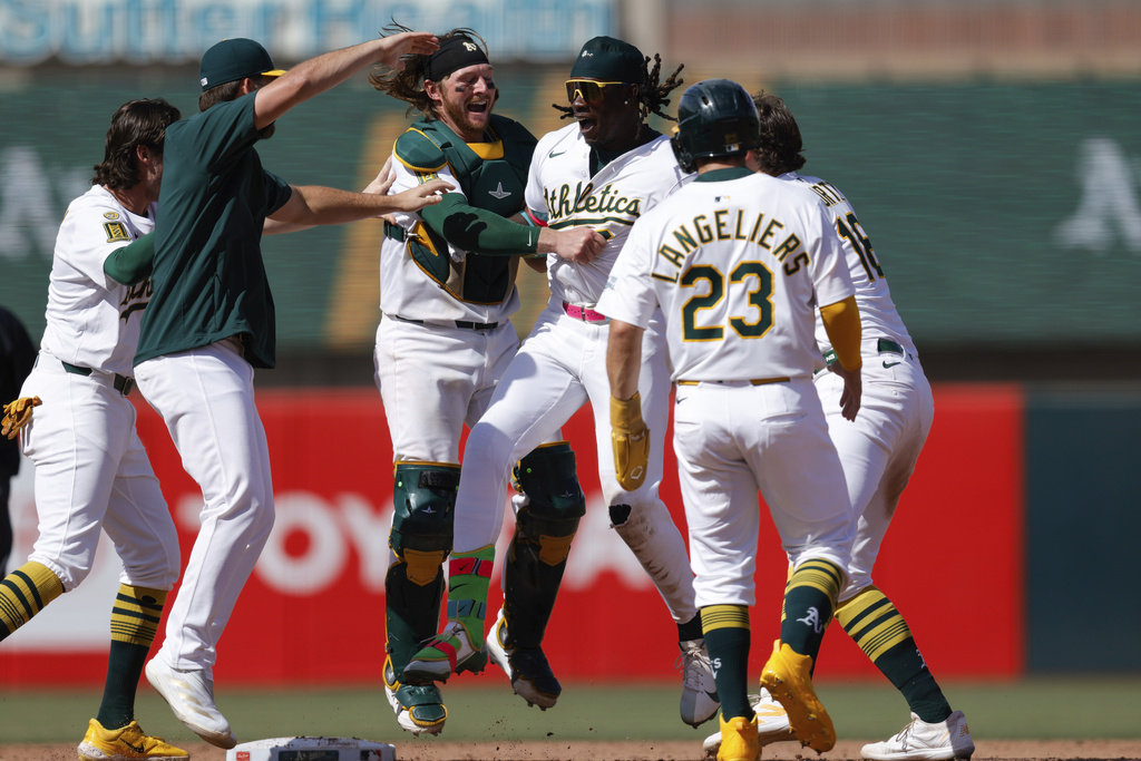 Athletics' Lawrence Butler, center, celebrates with teammates after hitting a game winning RBI single during the ninth inning of a baseball game against the Boston Red Sox Wednesday, Sept. 10, 2025, in West Sacramento, Calif. (AP Photo/Sergio Estrada)