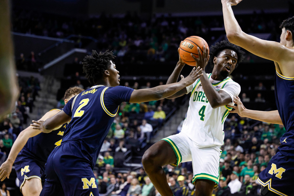 Oregon forward Dezdrick Lindsay (4), looks to pass against Michigan guard L.J. Cason (2) in the first half of an NCAA college basketball game in Eugene, Ore., Saturday, Jan. 17, 2026. (AP Photo/Thomas Boyd)