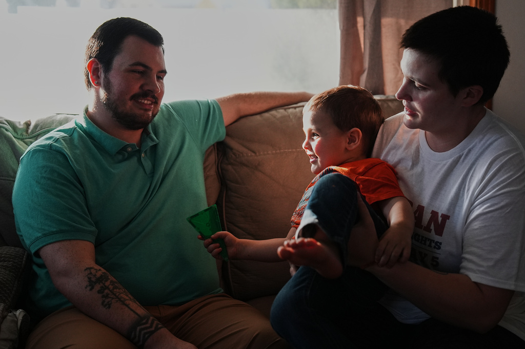 Morgan Carroll, right, relaxes at home with her son, River, center, and husband, Hunter, left, Tuesday, March 10, 2026, in Shelby, Ohio. (AP Photo/Joshua A. Bickel)