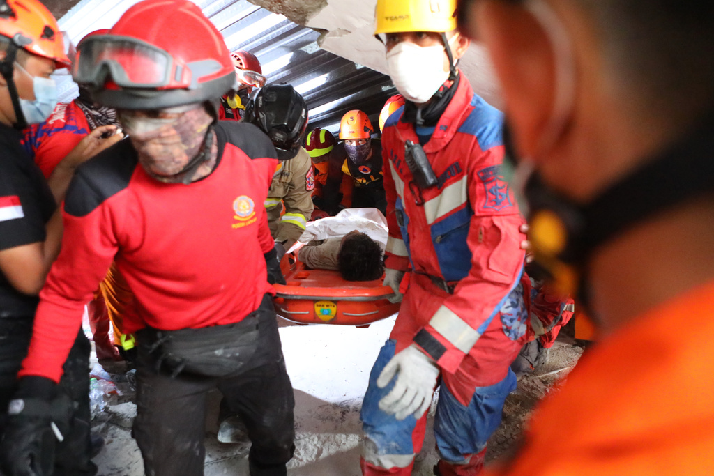 Rescuers carry a survivor who was pulled out from the rubble after a building under construction collapsed at an Islamic boarding school in Sidoarjo, East Java, Indonesia, Wednesday, Oct. 1, 2025. (AP Photo/Alam Syahirul)
