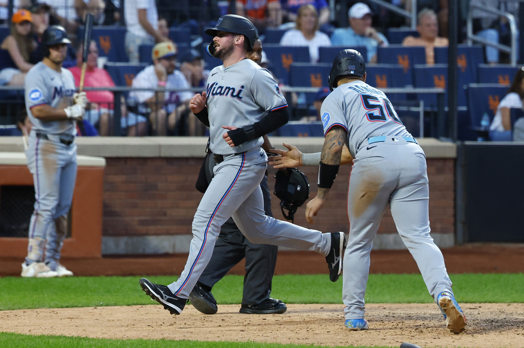 Miami Marlins' Liam Hicks scores after Agustín Ramírez (50) during the ninth inning of a baseball game against the New York Mets, Saturday, Aug. 30, 2025, in New York. (AP Photo/Noah K. Murray)