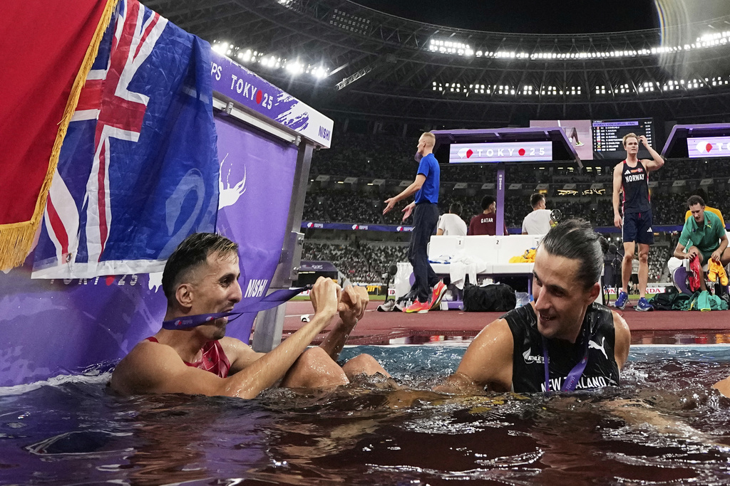 Gold medalist New Zealand's Geordie Beamish, right, sits with silver medalist Morocco's Soufiane El Bakkali after the men's 3,000 meters steeplechase final at the World Athletics Championships in Tokyo, Monday, Sept. 15, 2025. (AP Photo/Ashley Landis)