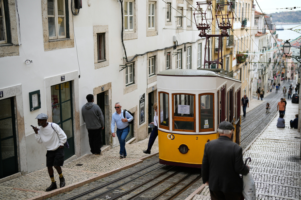 FILE - People walk past a parked Bica funicular in Lisbon, out of service after another streetcar derailed and crashed in the Portuguese capital killing multiple people and injuring several others, Oct. 30, 2025. (AP Photo/Armando Franca, File)