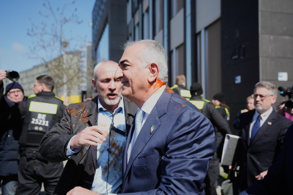 Iran's Reza Pahlavi, exiled son of Shah Reza Pahlavi, is protected by security after he was attacked with a red fluid, following a news conference in Berlin, Germany, Thursday, April 23, 2026. (AP Photo/Markus Schreiber)