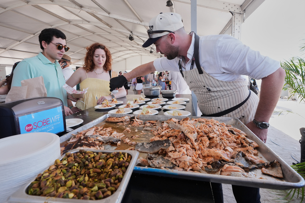 Chef Ryan O'Sullivan puts the finishing touches to samples of grilled Kvaroy salmon with fennel remoulade at the South Beach Wine and Food Festival Saturday, Feb. 21, 2026, in Miami Beach, Fla. (AP Photo/Marta Lavandier)