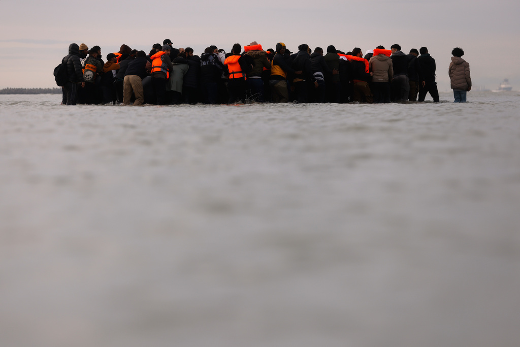 Migrants push a small boat in an attempt to reach Britain, Thursday, Nov. 6, 2025 in Gravelines, northern France. (AP Photo/Jean-Francois Badias)