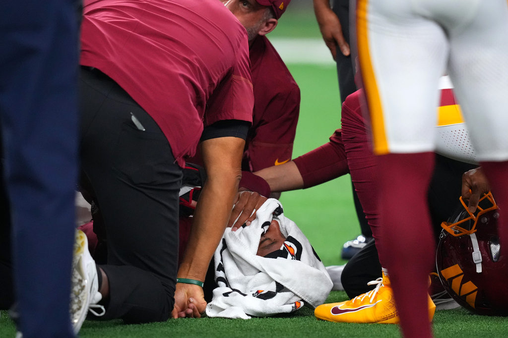 Trainers attend to Washington Commanders quarterback Jayden Daniels (5) after an apparent injury in the first half against the Dallas Cowboys during an NFL football game in Arlington, Texas, Sunday, Sept. 20, 2026. (AP Photo/Julio Cortez)
