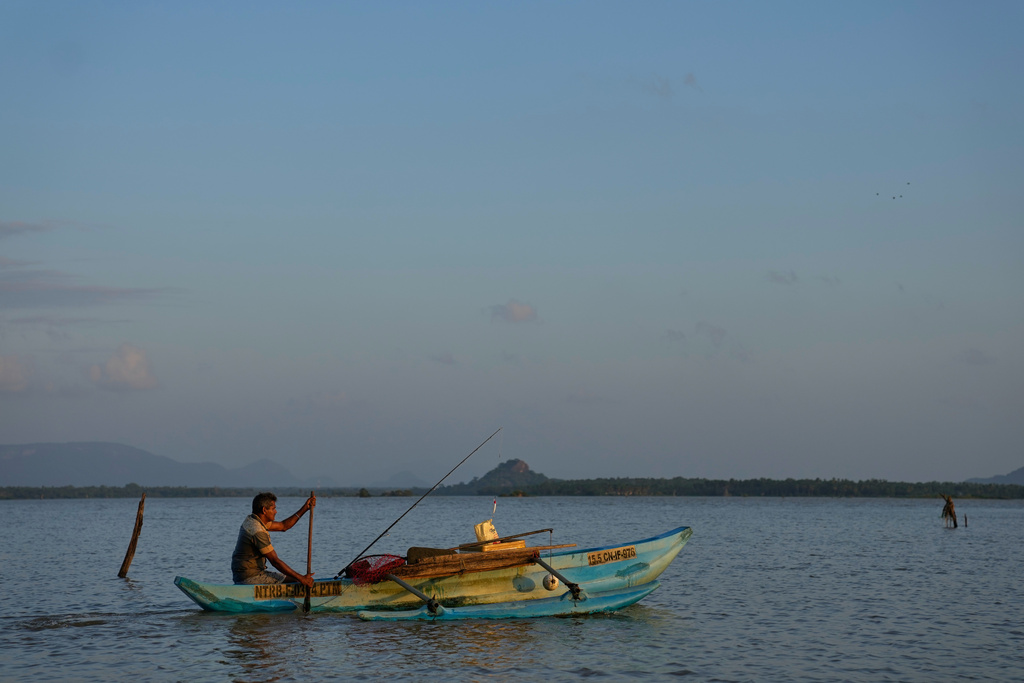 Ranjith Kumara paddles his catamaran searching for giant snakehead fish at the Deduru Oya Reservoir, in Walpaluwa village, Sri Lanka, Wednesday, Oct, 29, 2025. (AP Photo/Eranga Jayawardena)