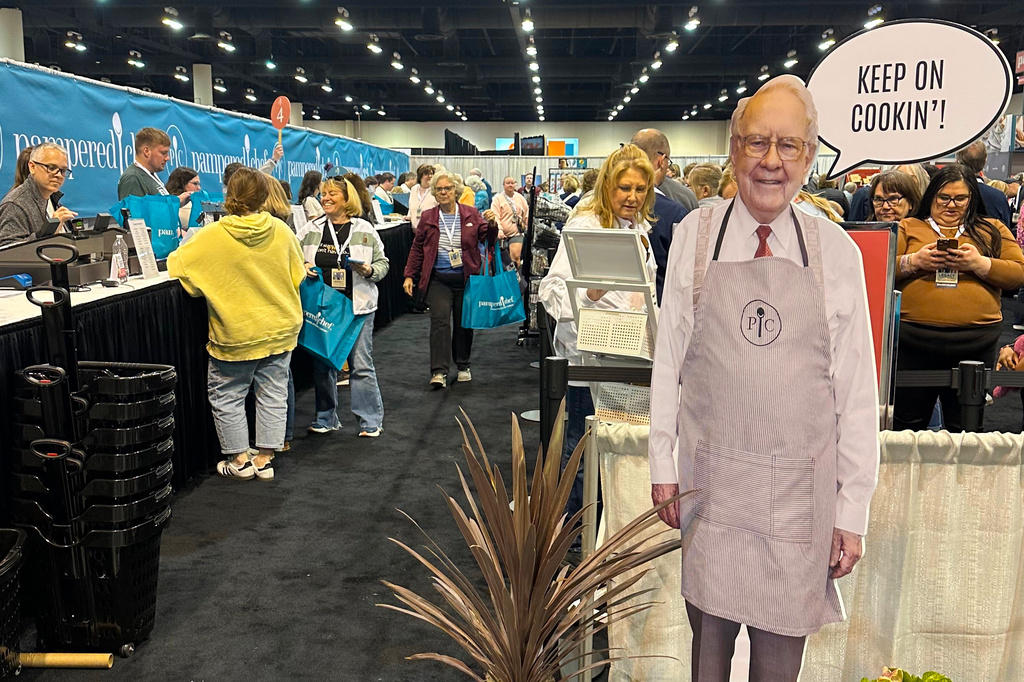 Berkshire Hathaway shareholders line up to buy products at the Pampered Chef booth behind a cutout of longtime CEO Warren Buffett who stepped down in January on Friday, May 1, 2026 in Omaha, Neb. (AP Photo/Josh Funk)