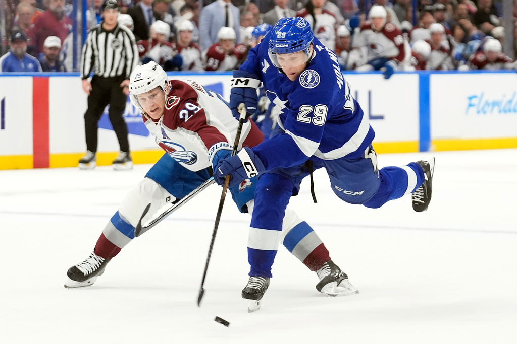 Colorado Avalanche center Nathan MacKinnon (29, left) blocks a shot by Tampa Bay Lightning right wing Pontus Holmberg (29) during the second period of an NHL hockey game Tuesday, Jan. 6, 2026, in Tampa, Fla. (AP Photo/Chris O'Meara)