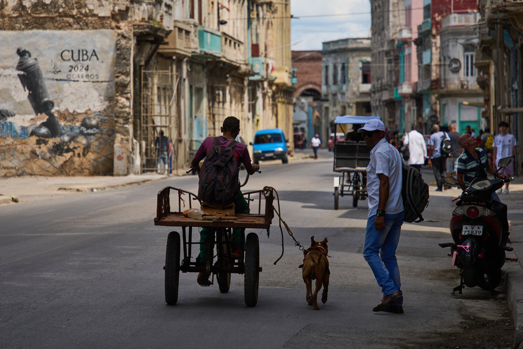 A man rides a tricycle with his leashed dog running alongside him during a blackout in Havana, Cuba, Monday, March 16, 2026. (AP Photo/Ramon Espinosa)