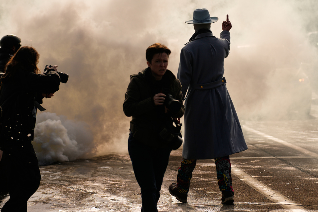 EDS NOTE: OBSCENITY - A man gestures as he walks toward a cloud of tear gas that was deployed by federal immigration officers Monday, Jan. 12, 2026, in Minneapolis. (AP Photo/John Locher)