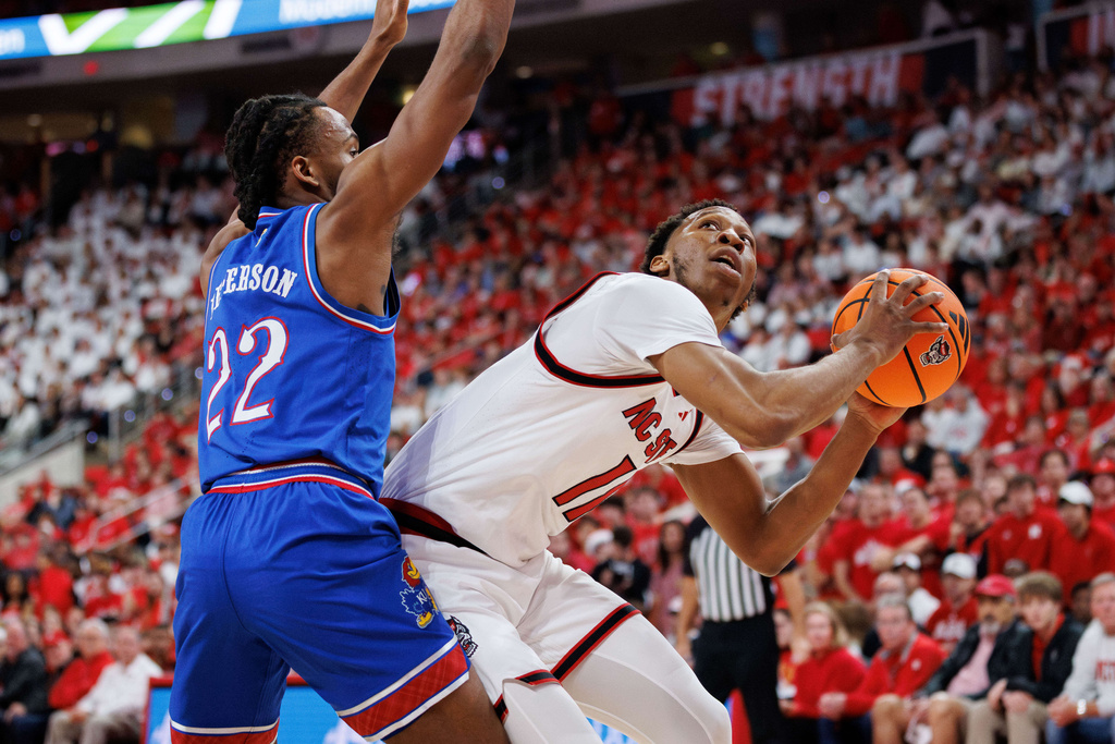 North Carolina State's Quadir Copeland, right, handles the ball as Kansas's Darryn Peterson (22) defends during the first half of an NCAA college basketball game in Raleigh, N.C., Saturday, Dec. 13, 2025. (AP Photo/Ben McKeown)