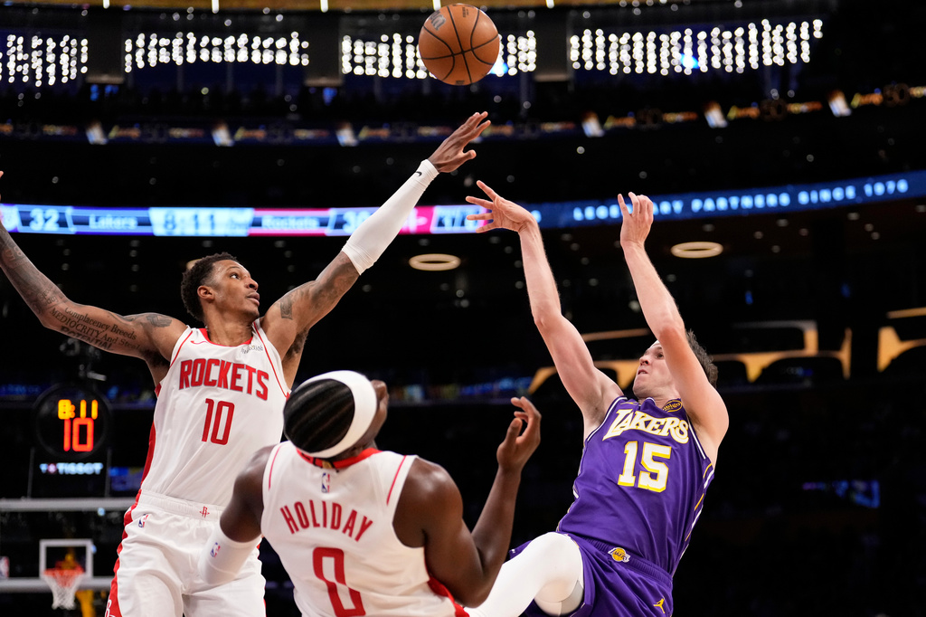 Los Angeles Lakers guard Austin Reaves, right, shoots as Houston Rockets forward Jabari Smith Jr., left, and guard Aaron Holiday defend during the first half in Game 5 of a first-round NBA playoffs basketball series Wednesday, April 29, 2026, in Los Angeles. (AP Photo/Mark J. Terrill)