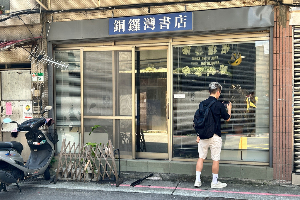 A journalist looks into the Causeway Bay Books bookstore near a banner which reads "Free Hong Kong" in Taipei, Taiwan on Friday, July 3, 2026. (AP Photo/Taijing Wu)