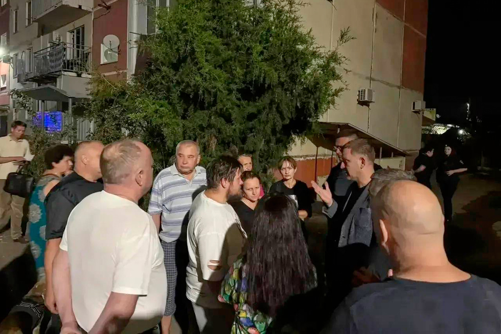 In this photo distributed by the head of Krasnodar Yevgeny Naumov official telegram channel, local citizens listen to a representative of administration standing near the apartment building after a Ukrainian drone attack on Karasunsky district in Krasnodar region, Monday, Aug. 24, 2026. (Head of Krasnodar Yevgeny Naumov official telegram channel via AP)