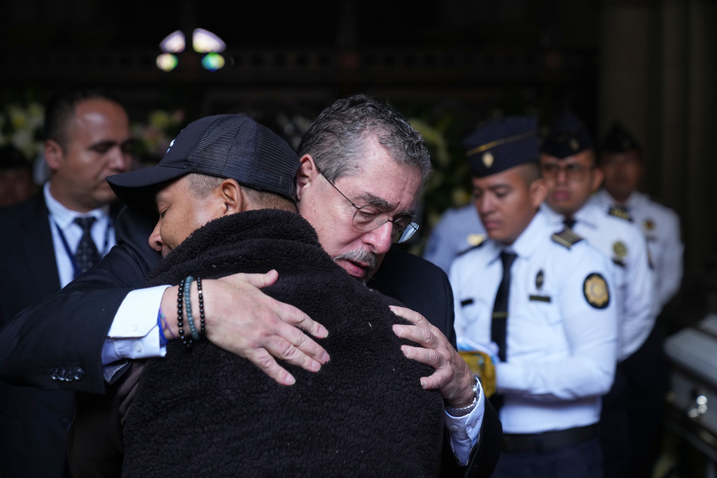 Guatemalan President Bernardo Arevalo comforts the relative of one of the police officers killed while retaking control of three prisons, during the wake for the officers at the Interior Ministry in Guatemala City, Monday, Jan. 19, 2026. (AP Photo/Moises Castillo)