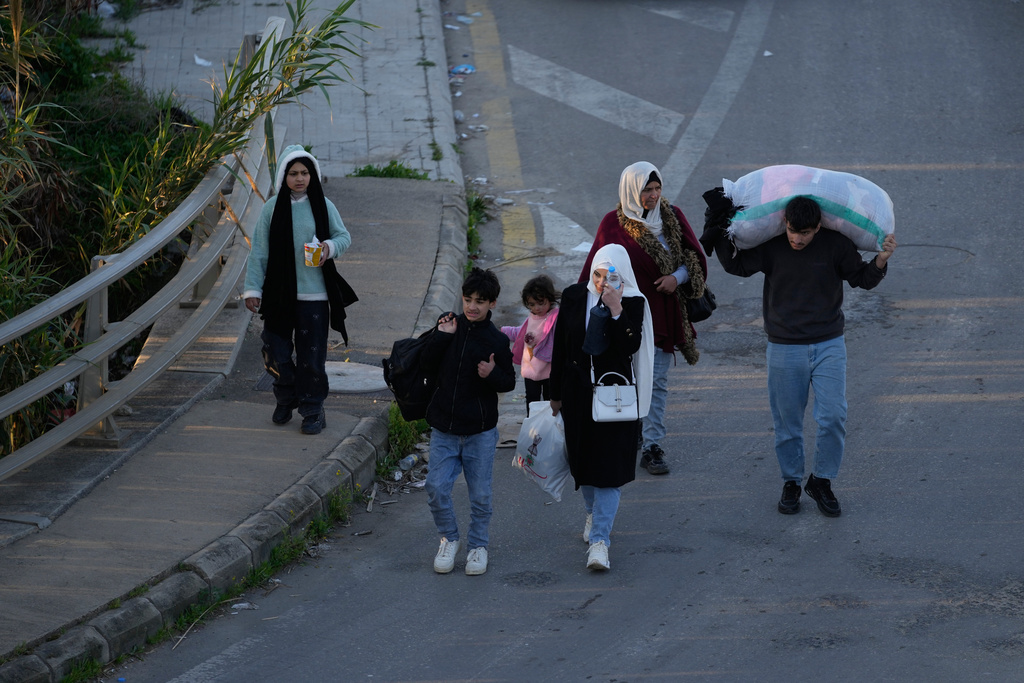 Displaced people carry their belongings fleeing Israeli strikes arrive in southern Lebanon arrive in the southern port city of Sidon, early Monday, March 2, 2026. (AP Photo/Mohammed Zaatari)