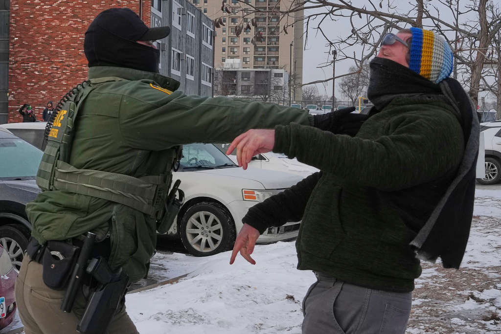 A person is pushed back by a federal agent working on the scene in Minneapolis, Sunday, Jan. 25, 2026. (AP Photo/Adam Gray)