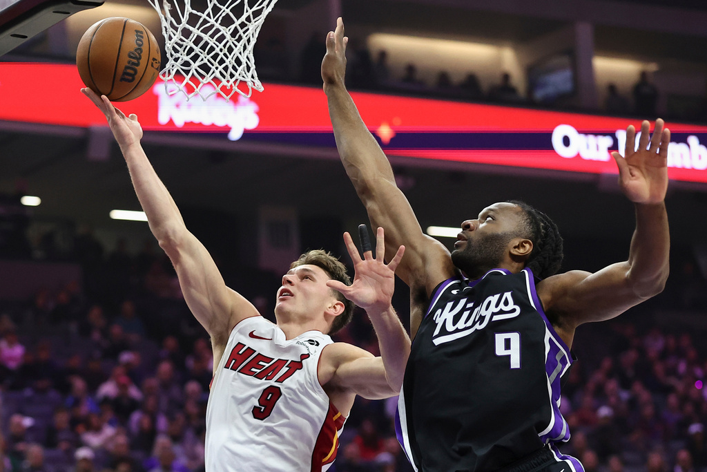 Miami Heat guard Pelle Larsson (9) makes a layup past Sacramento Kings forward Precious Achiuwa (9) during the first half of an NBA basketball game Tuesday, Jan. 20, 2026, in Sacramento, Calif. (AP Photo/Sara Nevis)