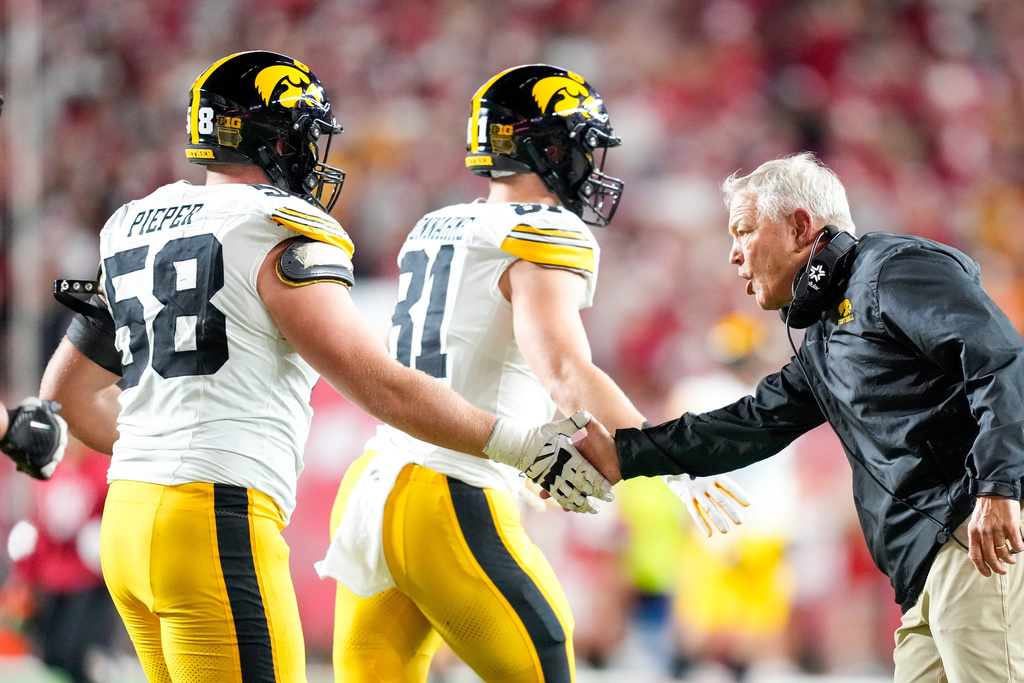 Iowa coach Kirk Ferentz, right, shakes hands with Kade Pieper, left, during the first half of an NCAA college football game against Wisconsin, Saturday, Oct. 11, 2025, in Madison, Wis. (AP Photo/Andy Manis)