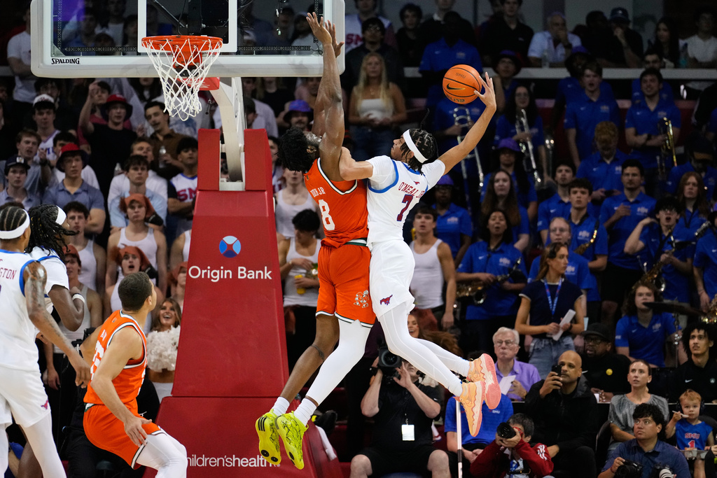 SMU forward Jermaine O'Neal Jr. (7) is challenged on a dunk attempt by Miami center Ernest Udeh Jr. (8) in the first half of an NCAA college basketball game in Dallas, Wednesday, March 4, 2026. (AP Photo/Tony Gutierrez)