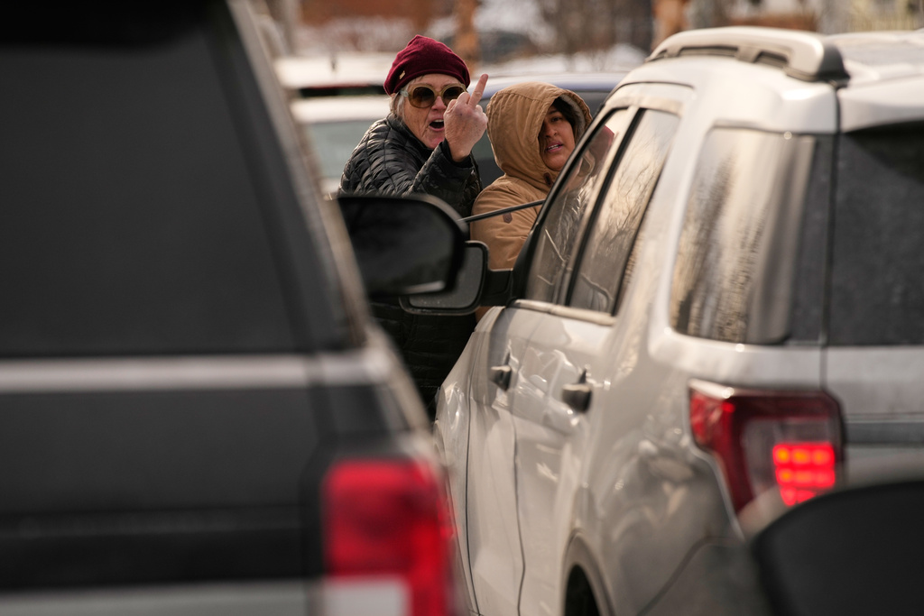 EDS NOTE: OBSCENITY - A woman gestures at federal immigration officers as they make an arrest Sunday, Jan. 11, 2026, in Minneapolis. (AP Photo/John Locher)