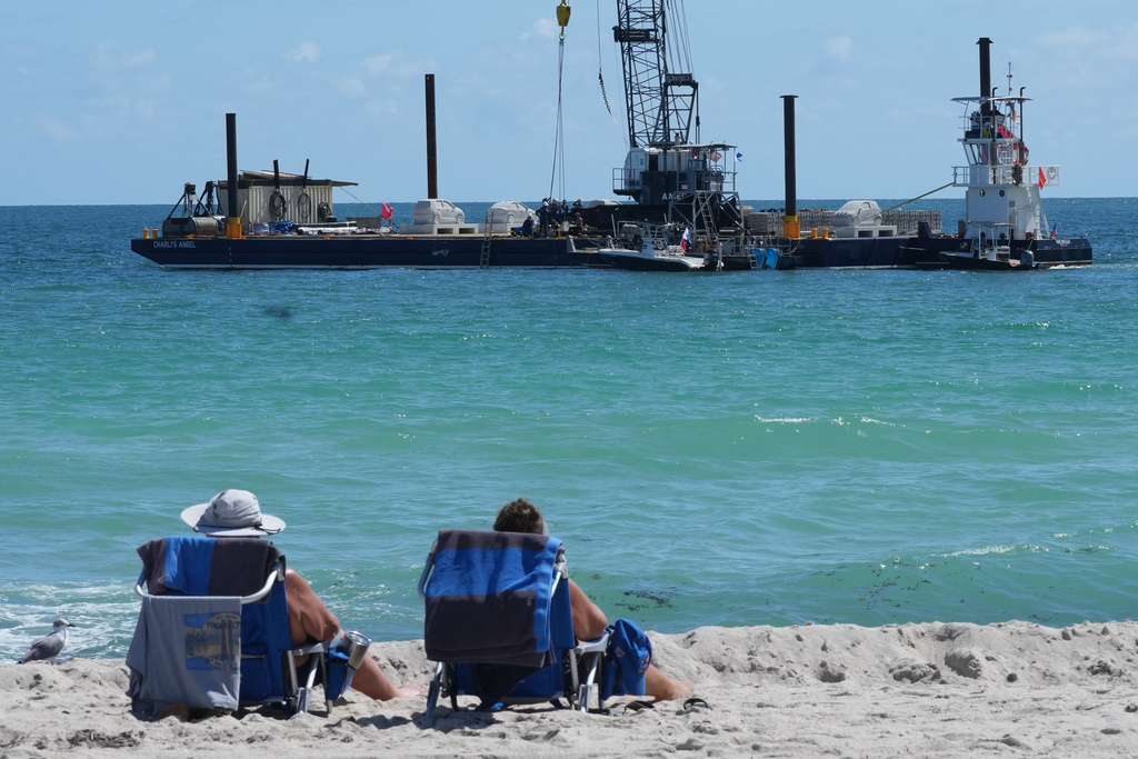Beachgoers watch as an underwater sculpture park is deployed off South Beach Tuesday, Oct. 21, 2025, in Miami Beach, Fla. (AP Photo/Marta Lavandier)