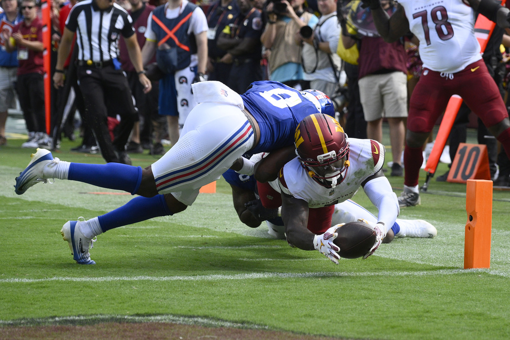 Washington Commanders wide receiver Deebo Samuel (1) diving in to score a touchdown against New York Giants safety Jevon Holland (8) during the second half of an NFL football game, Sunday, Sept. 7, 2025, in Landover, Md. (AP Photo/Nick Wass)
