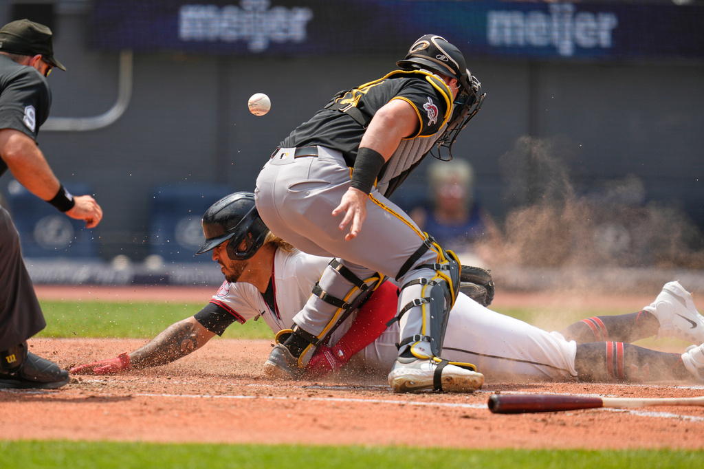Cleveland Guardians' Gabriel Arias, center, slides safely into home plate to score in front of home plate umpire Alex MacKay, left, as Pittsburgh Pirates catcher Henry Davis, right, loses the ball in the third inning of a baseball game in Cleveland, Sunday, July 19, 2026. (AP Photo/Sue Ogrocki)